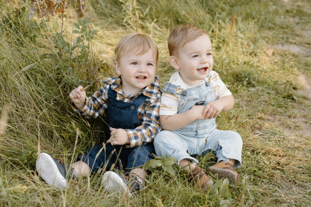 two toddler boys posing together in the grass